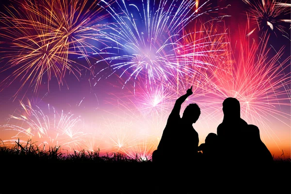 Familia feliz sentada en el suelo y viendo los fuegos artificiales Imagen De Stock