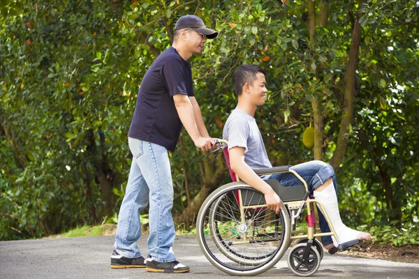 Jeune homme assis sur un fauteuil roulant avec son frère — Photo