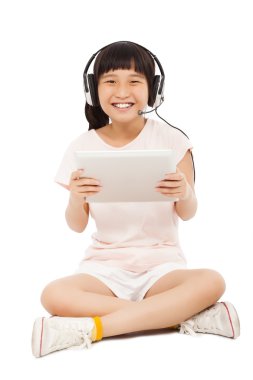 küçük kız bir tablet kulaklık ile tutarak oturan