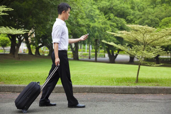 Affärsman promenader och använda en telefon på väg — Stockfoto