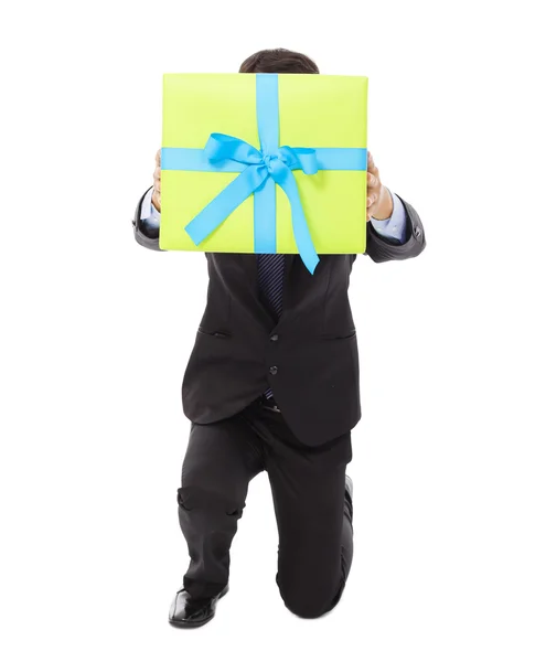 Empresario sosteniendo una caja de regalo y arrodillado  . — Foto de Stock