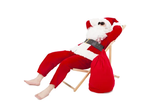 Veselé Vánoce santa claus, sedí na židli s taštička — Stock fotografie