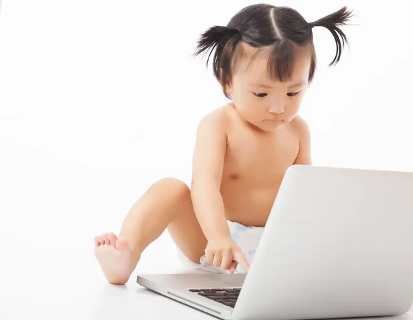 Niño pequeño sentado jugando en una computadora portátil . — Foto de Stock