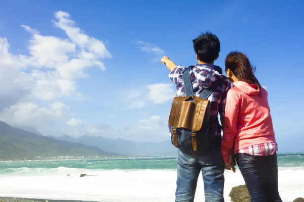 Vista trasera de la joven pareja mirando y apuntando al cielo en el be —  Fotos de Stock