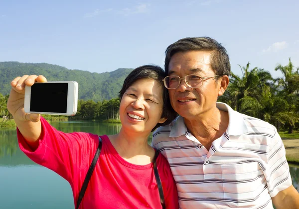 Couple de personnes âgées prenant une photo par eux-mêmes à l'extérieur — Photo