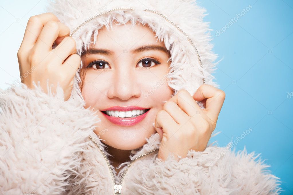 smiling asian girl with winter wear sweater.isolated on blue bac