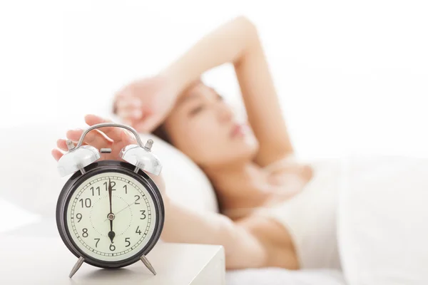 若い女性がベッドの上の目覚まし時計をオフにします。 — ストック写真