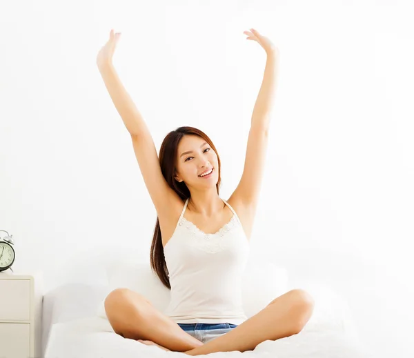 Happy young asian woman stretching in bed — Stock Photo, Image