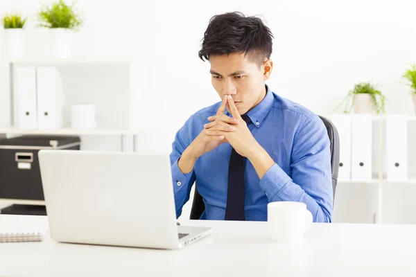 Joven asiático hombre de negocios viendo ordenador portátil y pensando —  Fotos de Stock