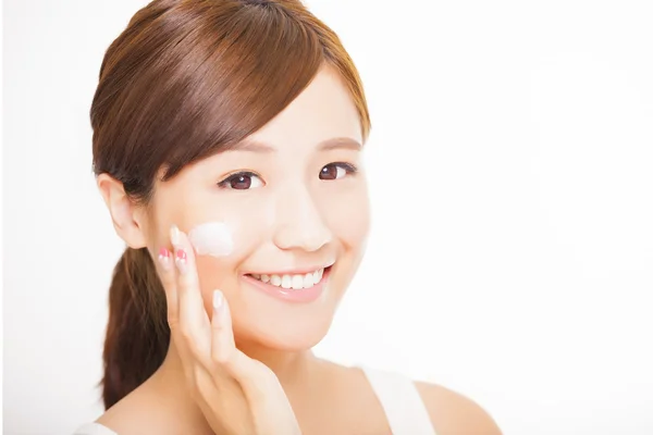 Beautiful young woman applying cosmetic cream  on her face — Stock Photo, Image