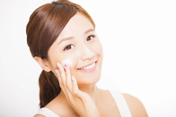 Bela jovem aplicando creme cosmético em seu rosto — Fotografia de Stock
