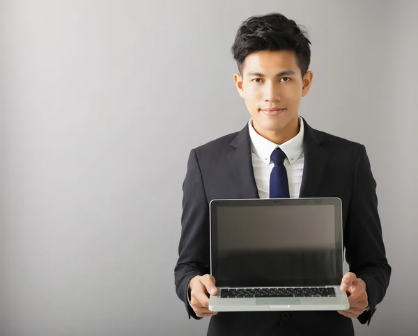 Joven sonriente hombre de negocios mostrando portátil —  Fotos de Stock