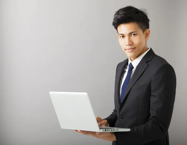 Jeune homme d'affaires souriant tenant ordinateur portable — Photo