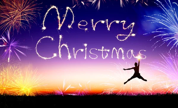 Young man jumping and drawing the merry christmas — Stock Photo, Image