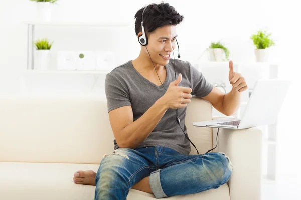 Jovem homem sentado no sofá e usando laptop — Fotografia de Stock