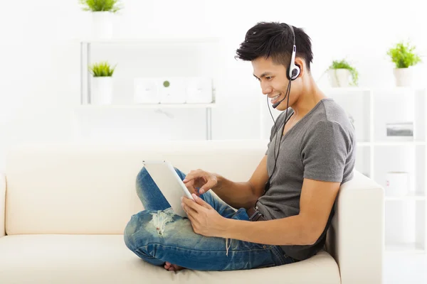 Jovem Homem sentado no sofá e usando tablet pc — Fotografia de Stock