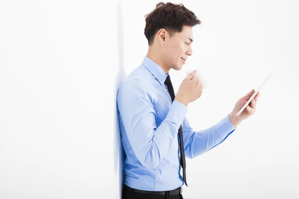 Jungunternehmer hält Tablet in der Hand und lehnt an weiße Wand — Stockfoto