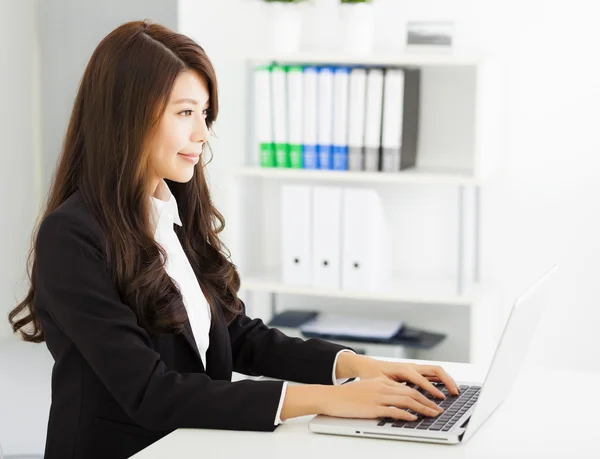 Улыбающаяся молодая деловая женщина, работающая с ноутбуком — стоковое фото