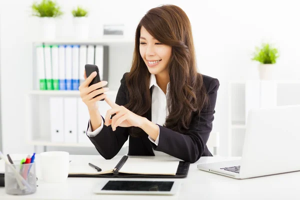 Zufriedene Geschäftsfrau mit dem Smartphone im Büro — Stockfoto