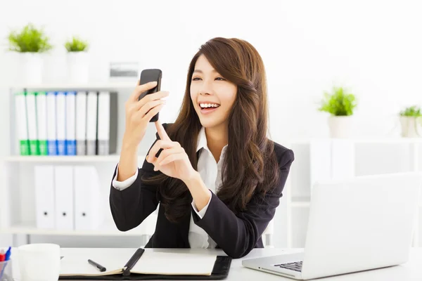Femme d'affaires heureuse en utilisant le téléphone intelligent dans le bureau — Photo