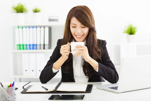 Beautiful young business woman drinking coffee in office — Stock Photo, Image