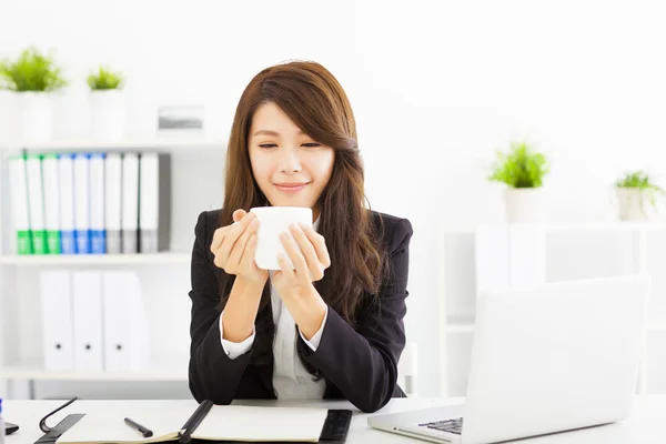 Schöne junge Geschäftsfrau trinkt Kaffee im Büro — Stockfoto