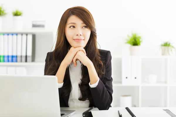 Smiling young business woman thinking in the office — Stock Photo, Image