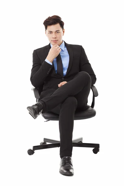 Молодой бизнесмен сидит в кресле и думает: — стоковое фото