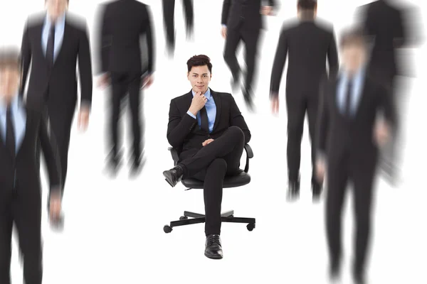 Ung affärsman sitter i en stol och människor gå — Stockfoto