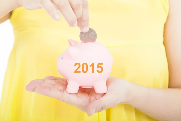 Hand putting coin into a piggy bank for 2015 investment concept — Stock Photo, Image