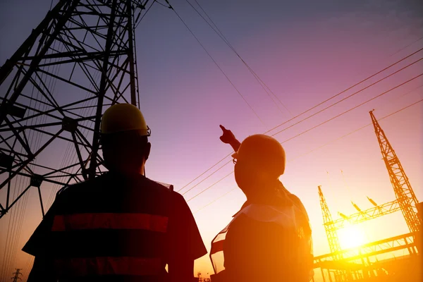 Dos trabajadores observando la torre de energía y la subestación con puesta de sol b — Foto de Stock