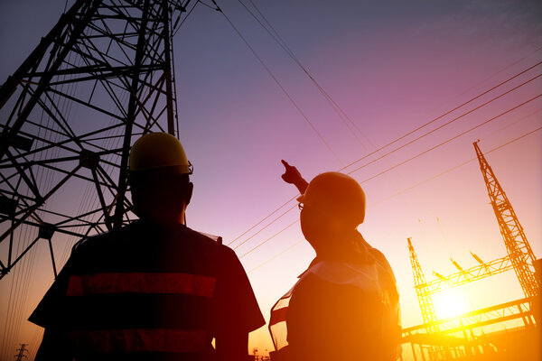 two worker watching the power tower and substation with sunset b