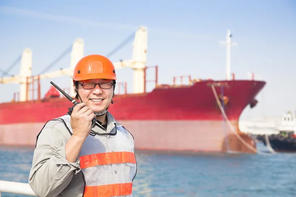 Sonriente trabajador portuario tholding radio y fondo del barco — Foto de Stock