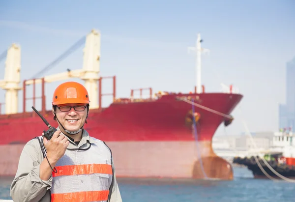 Sorrindo dock trabalhador tholding rádio e fundo do navio — Fotografia de Stock