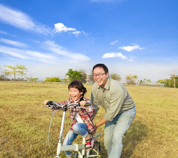 Счастливый отец учит маленькую девочку ездить на велосипеде — стоковое фото