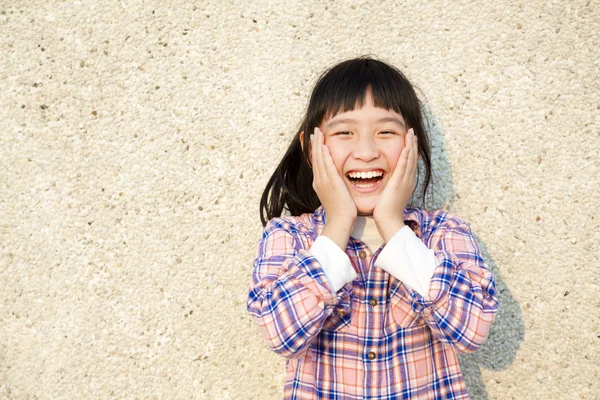 Glad liten tjej stå inför väggen — Stockfoto