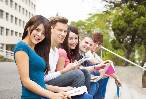 Šťastná mladá skupina studentů sedí na schodech — Stock fotografie