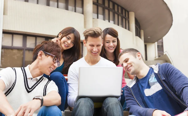 Jovem grupo feliz de estudantes assistindo o laptop — Fotografia de Stock