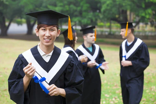 Gelukkig studenten in afstuderen toga op de universiteitscampus — Stockfoto