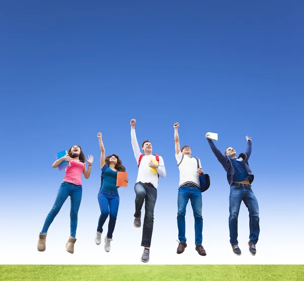 Happy young group of students jumping together — Stock Photo, Image