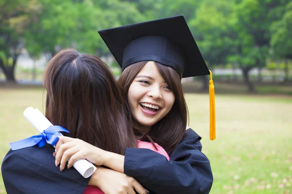 Giovane laureata abbracciare il suo amico alla cerimonia di laurea — Foto Stock