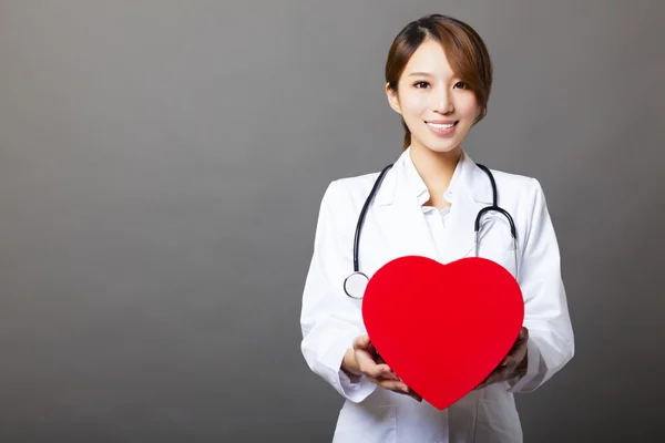 Smiling asian female doctor with heart — Stock Photo, Image