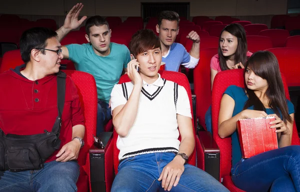 Young men talking on the phone while watching movie at the cinem — Stock Photo, Image