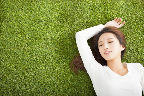 Ontspannen jonge vrouw liggen op het gras — Stockfoto