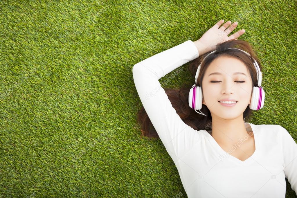 Relaxed woman listening to the music with headphones lying on th