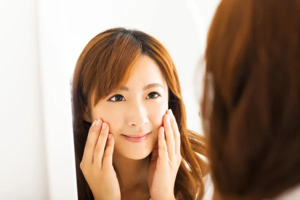 Smiling young woman looking mirror in  bedroom — Stock Photo, Image