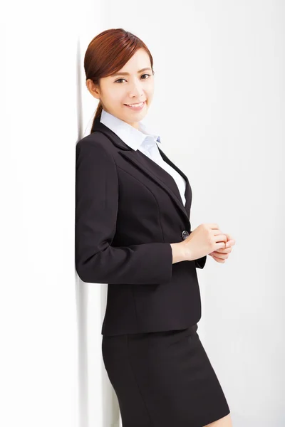 Young businesswoman leaning against white wall in office — Stock Photo, Image