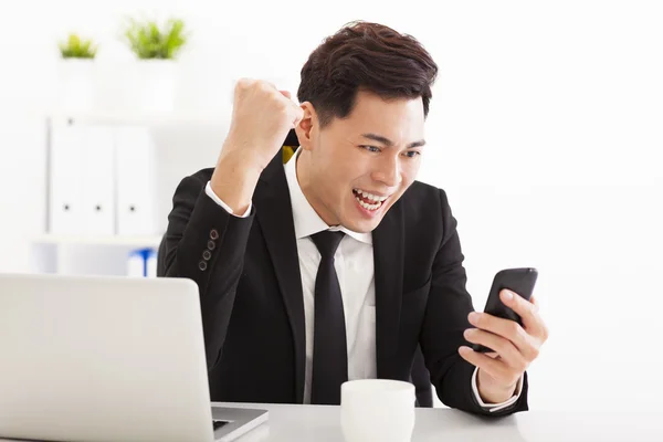 Homme d'affaires heureux regardant le téléphone intelligent dans le bureau — Photo