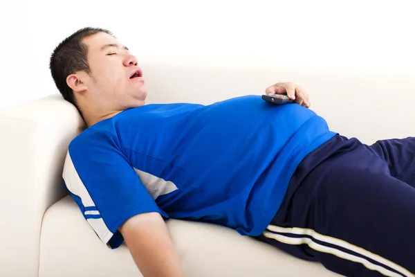 Homem gordo dormir no sofá e segurando tv controle remoto — Fotografia de Stock