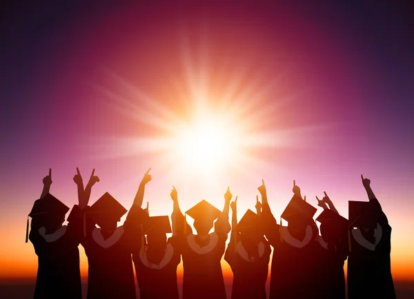 Silhouette degli studenti che festeggiano la laurea guardando il sunli — Foto Stock